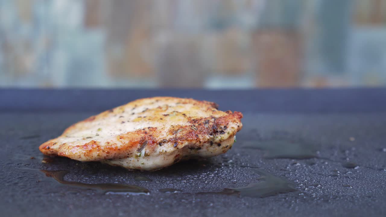 Gustosa carne di pollo alla griglia su piastra con fumo sullo sfondo, primo piano laterale.