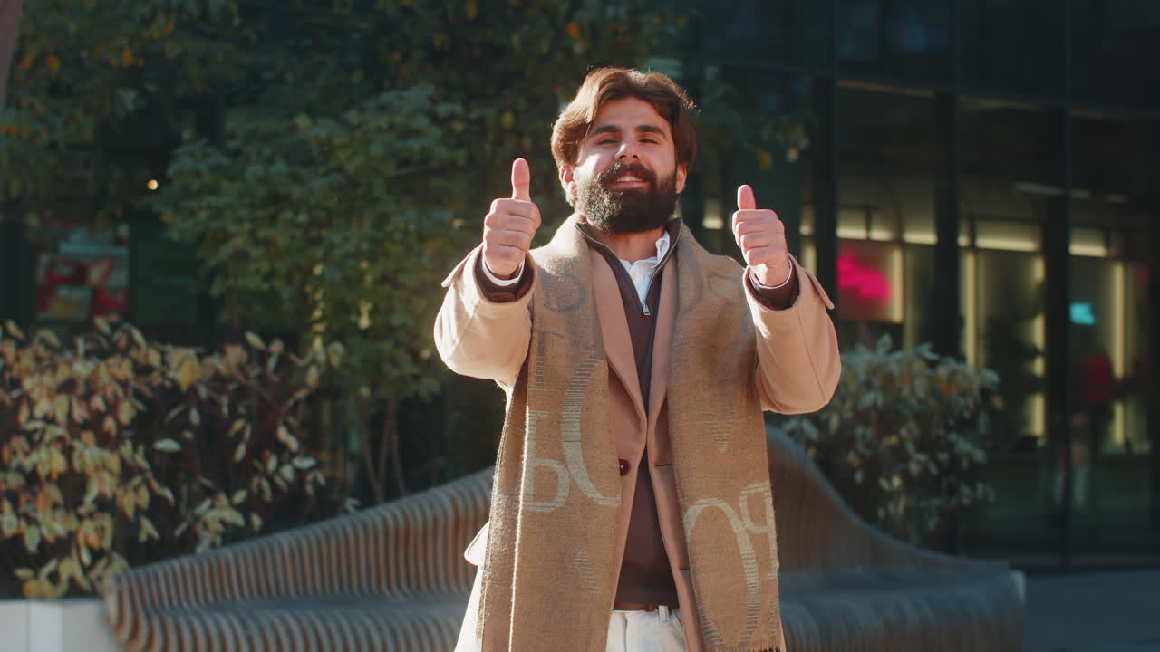 Happy indian business man showing thumb up gives positive reply standing on downtown city street