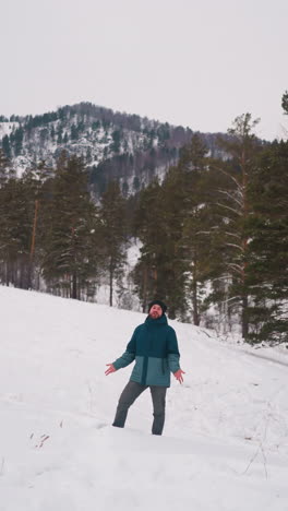 happy man enjoys winter nature of gorny altai standing on slope covered with white snow. tourist contemplates giant forestry mountains in highland