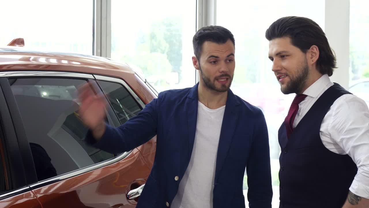 dos amigos hombres discutiendo un coche nuevo en el salón del concesionario