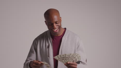 studio shot of excited mature man celebrating winning cash prize throwing handful of 100 dollar bills in the air 2