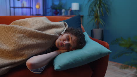 tired brunette young woman lying down in bed taking a rest at home, napping falling asleep on sofa