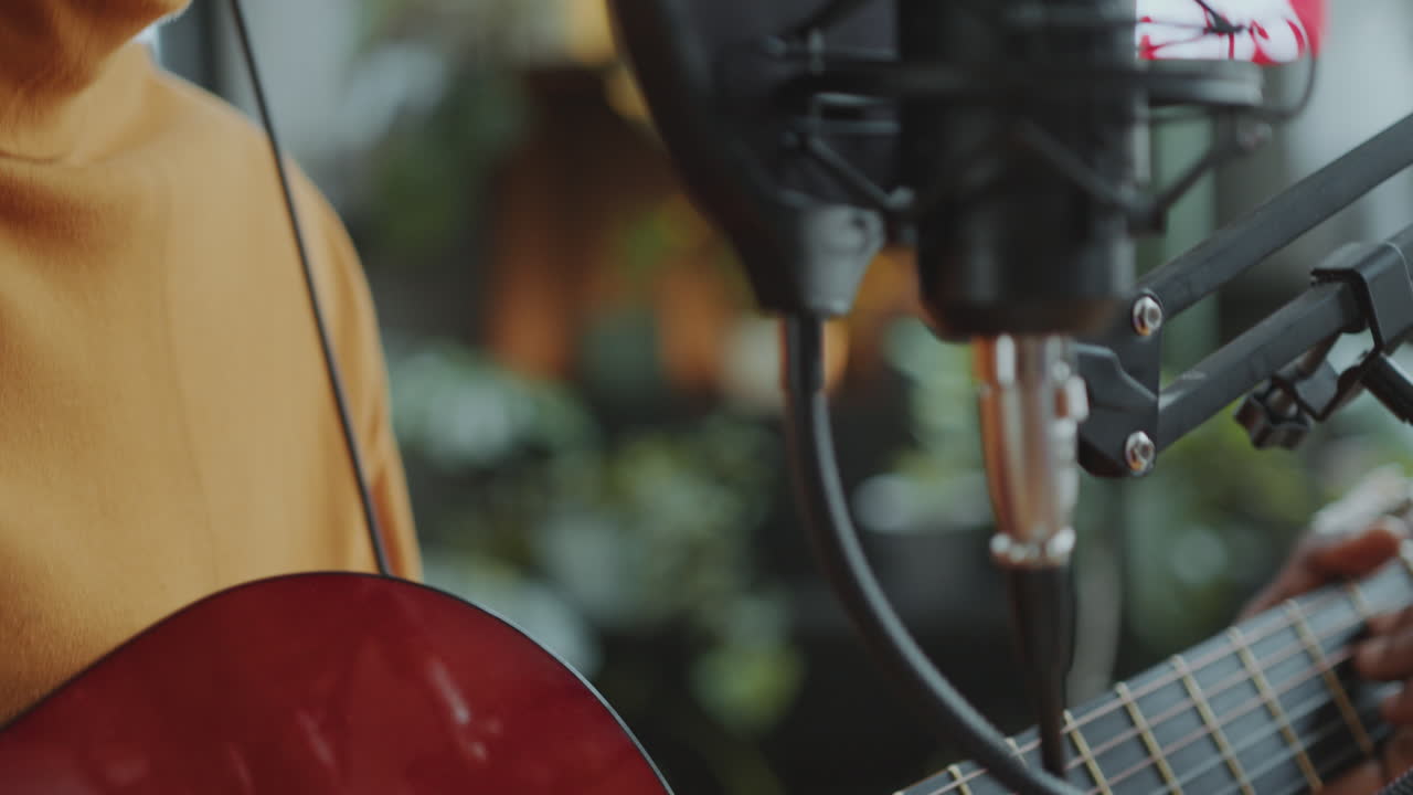 아프리카계 미국인 뮤지션이 라디오 스튜디오에서 기타로 노래를 연주하고 있습니다.