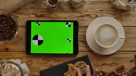 tableta digital con pantalla verde colocada horizontalmente en un escritorio de madera. comer, beber, trabajar