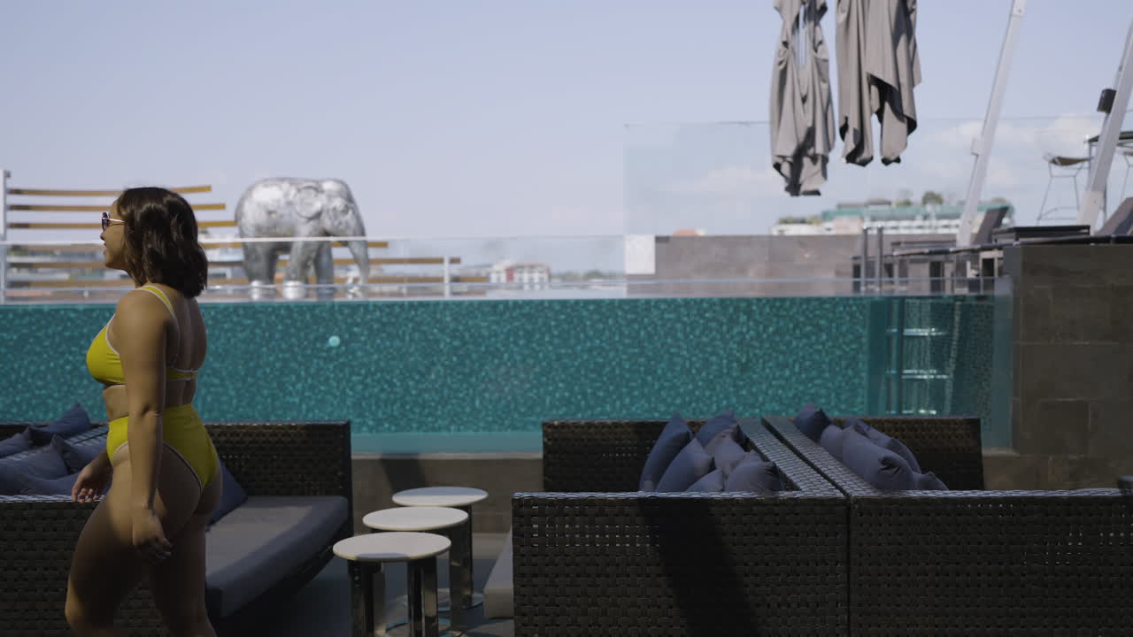 foto reveladora de una mujer joven en bikini explorando el área de descanso al aire libre