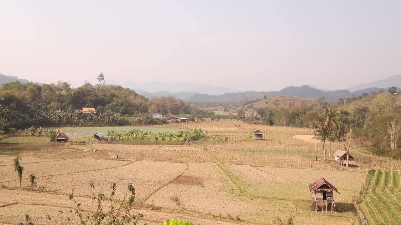 Memandang ke bawah ke sawah terasering hijau cerah di kota pegunungan Nong Khiaw di Laos, Asia Tenggara.