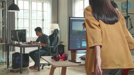 back view of asian female video editor start works with footage and sound on her personal computer in office