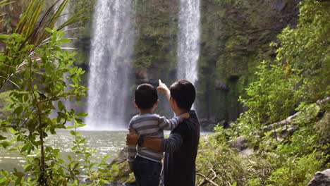 cinemagraph of child in his father's arms looks at waterfalls