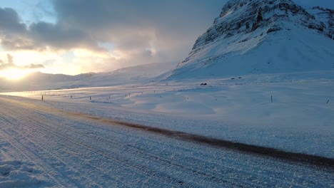 wide shot of  car driving on iceland road with snow white mountains and sunset countryside, winter time. 4k