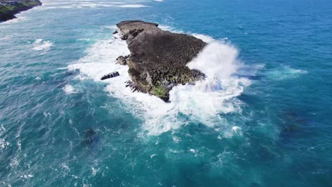 Una-Toma-Aérea-De-Un-Islote-Accidentado-Golpeado-Por-Poderosas-Olas-Del-Océano.