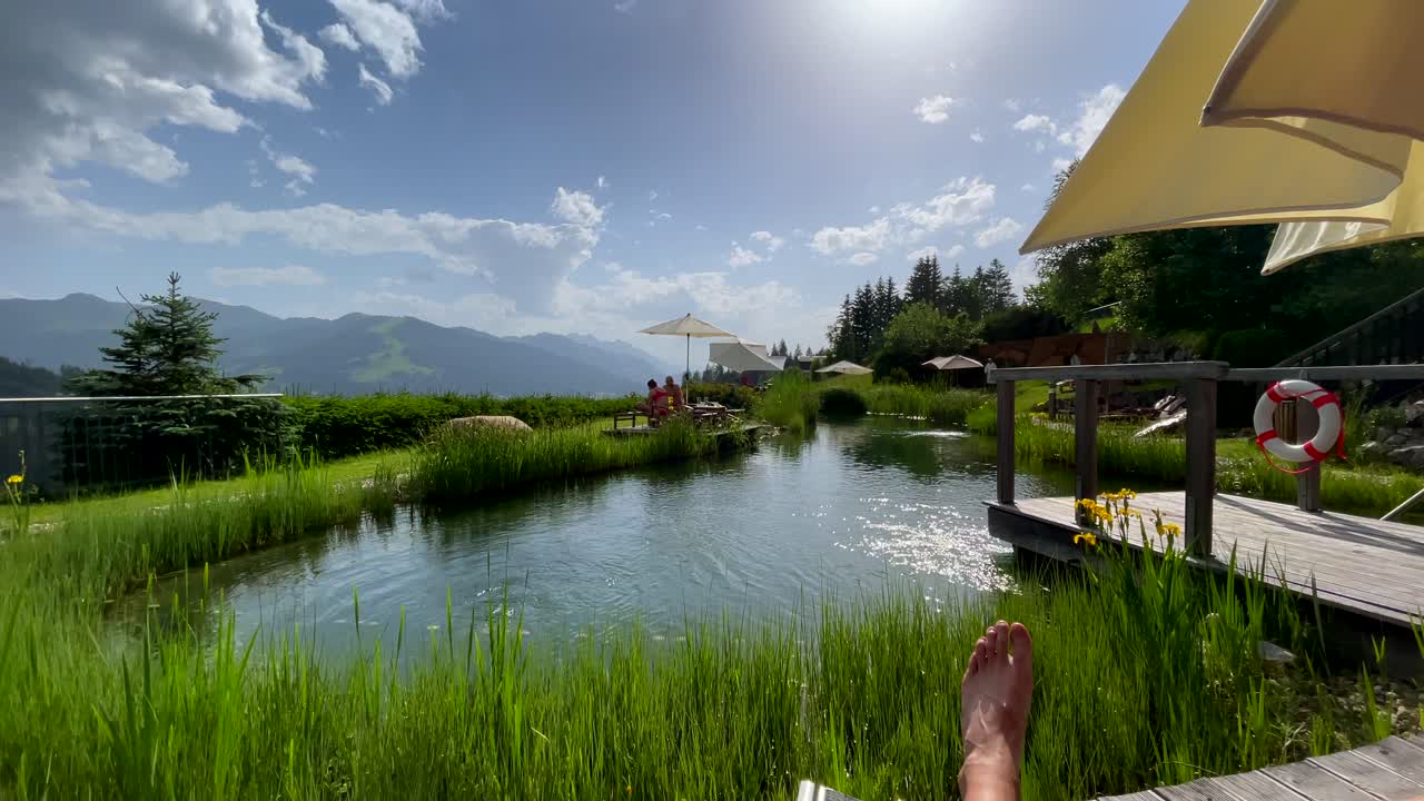 푸른 하늘과 햇빛이 비치는 동안 아름다운 자연 호수에서 쉬고 있는 사람들을 보여주는 pov 팬 샷