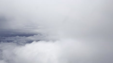 aerial shot above soft white clouds with a glimpse of blue sky and distant horizon