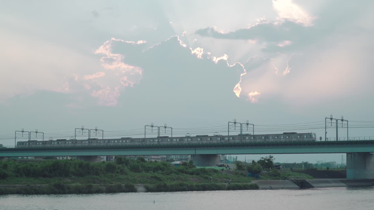 일몰 시간에 일본 도쿄의 타마가와 강을 가로지르는 금속 다리를 지나가고 여행하는 jr 열차