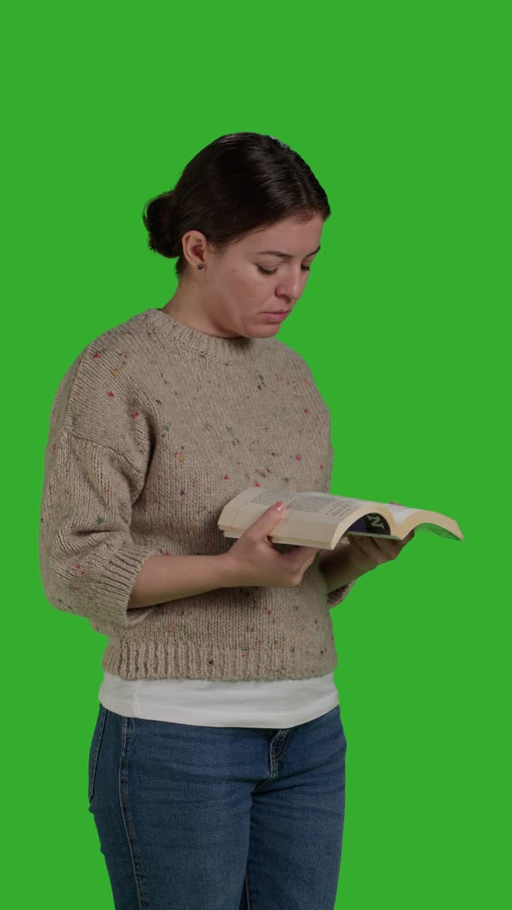 Vertical video: Side view of young person with action book reading in studio