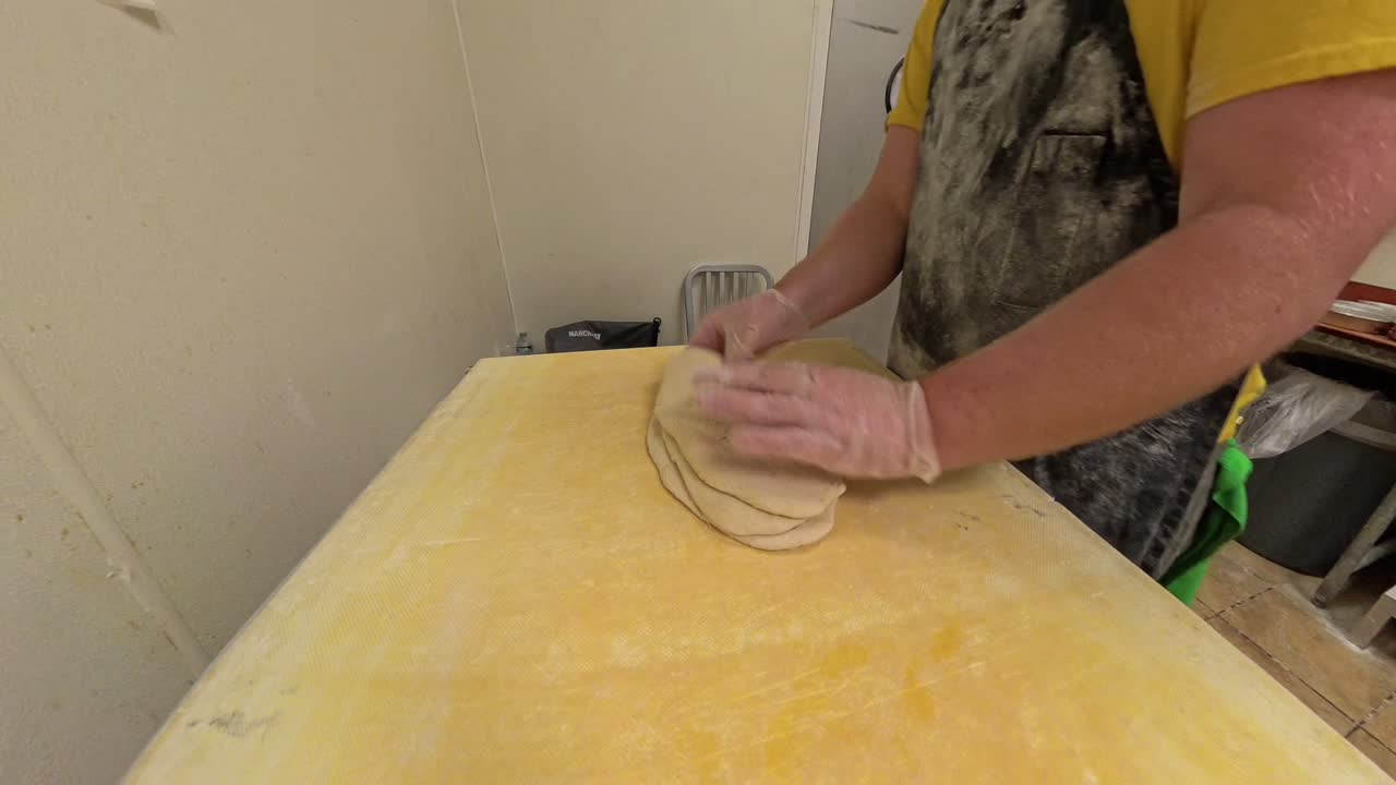 Raw pizza dough being stacked on a machine.