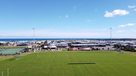 Luftaufnahme-über-Die-Rugbyplätze-Im-Halesworth-Park-Mit-Dem-Alkimos-College-Und-Dem-Meer-Im-Hintergrund