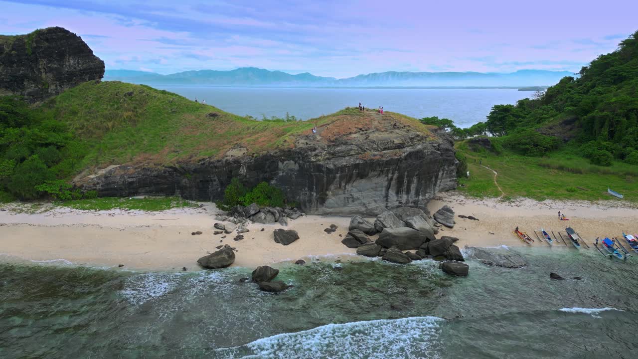 관광객을 태운 지역 보트가 다키트 해변의 카포네스 섬 산맥에 도착했습니다.