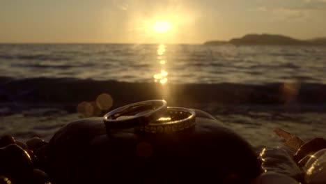 wedding rings by the sea at sunset