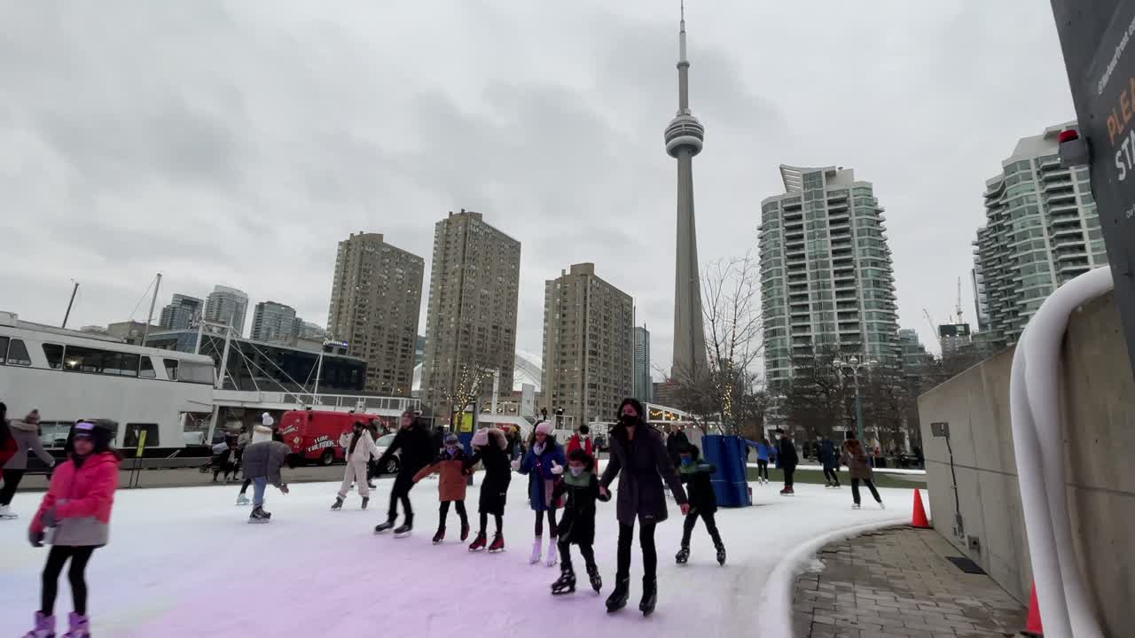 Toronto Harbourfront skating during winter with CN Tower in background - January 2022 - Skating in urban city during winter in Ontario, Canada on new years near waterfront