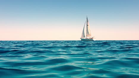 low-angle view of small white yacht boat sailing slowly in calm open sea