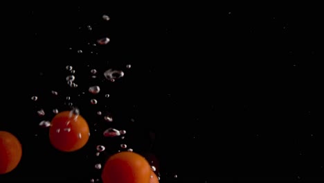 tomatoes falling into water super slowmotion, black background, lots of air bubbles, 4k240fps