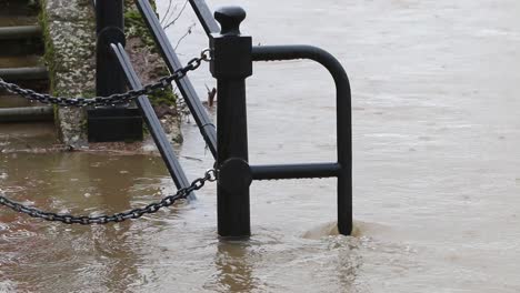 el río severn fluye sobre las barandillas y el sendero a lo largo de sus orillas mientras cae más lluvia