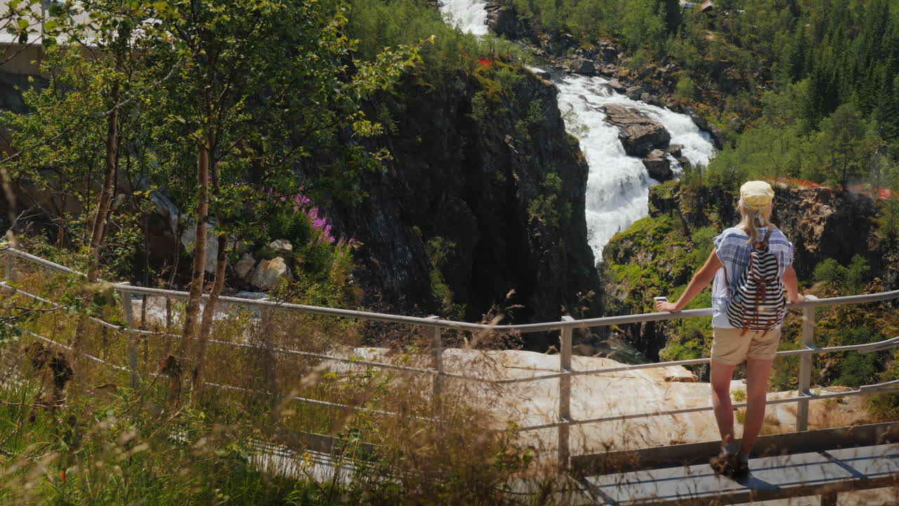 En kvinna tittar på det majestätiska vattenfallet Vøringsfossen i Norge. Skandinaviens imponerande skönhet.