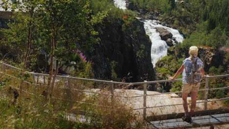 a woman looks at the majestic waterfall of woringsfossen in norway impressive beauty of scandinavian