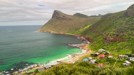 Smitswinkel-Bay-small-beach-town-Cape-of-Good-Hope-most-southern-point-large-mountain-cliffside-coastline-scenic-South-Africa-Cape-Town-daytime-beauty-deep-blue-aqua-lush-summertime-pan-left