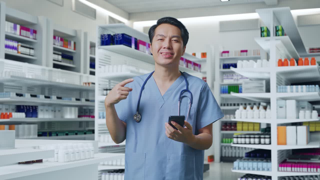 약국 에서 스마트폰 을 손 으로 가리키는 스테토스코프 를 들고 있는 아시아인 남성 의사