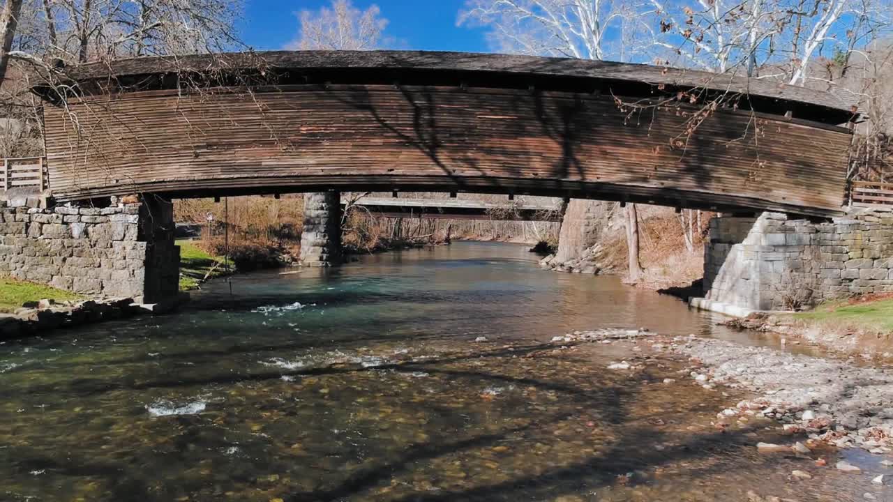 나무 덮힌 다리 아래 얕은 급류가 있는 아름다운 산줄기