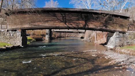 hermoso arroyo de montaña con rápidos poco profundos bajo un puente cubierto de madera