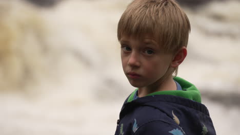 slow motion portrait of a little boy watching the fury of white water rapids