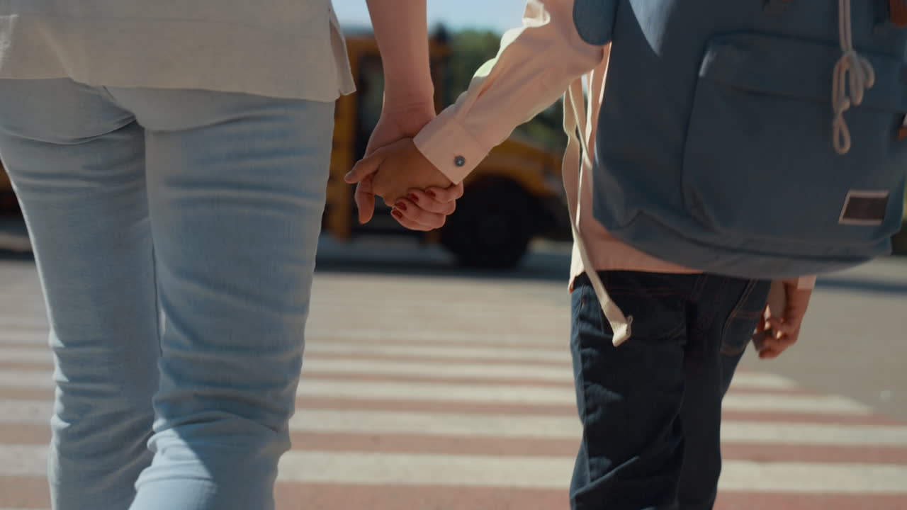 엄마와 아들의 다리가  ⁇ 는 보행자 교차로 가 ⁇ 게. 가족이 손을 잡고.