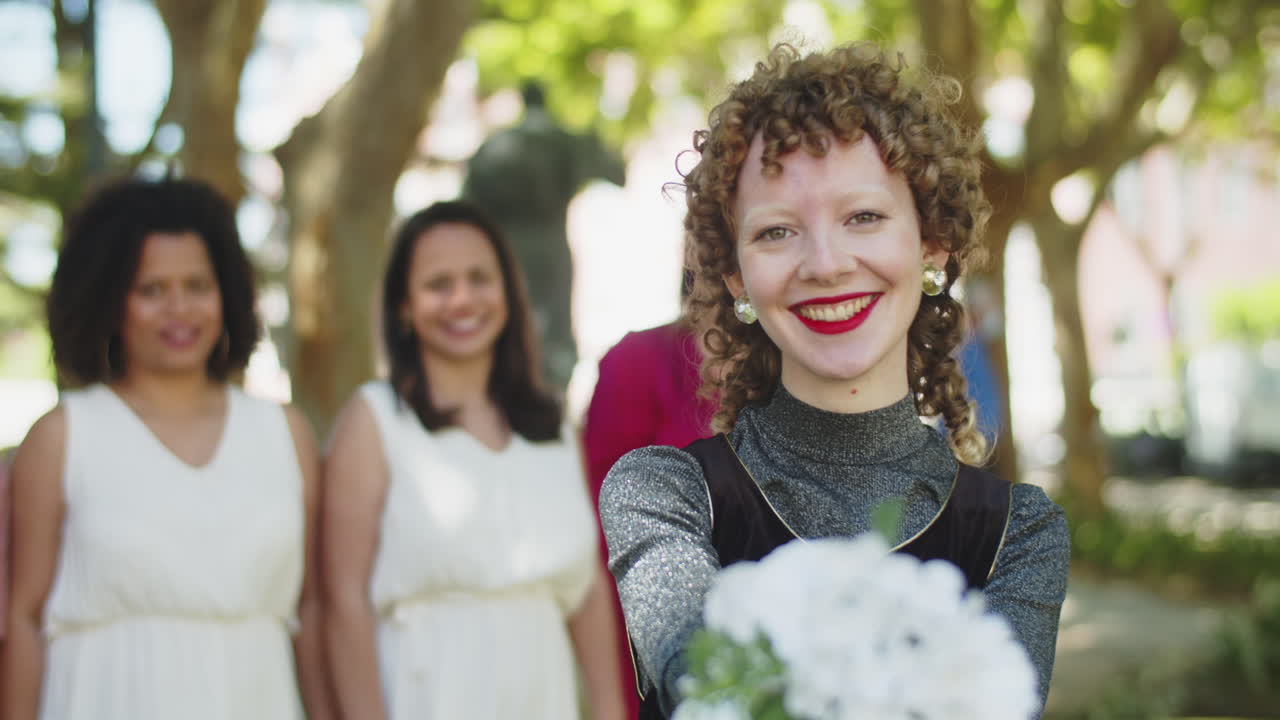 카메라를 보고 신부 부케를 보여주는 웃는 신부 들러리의 초상화