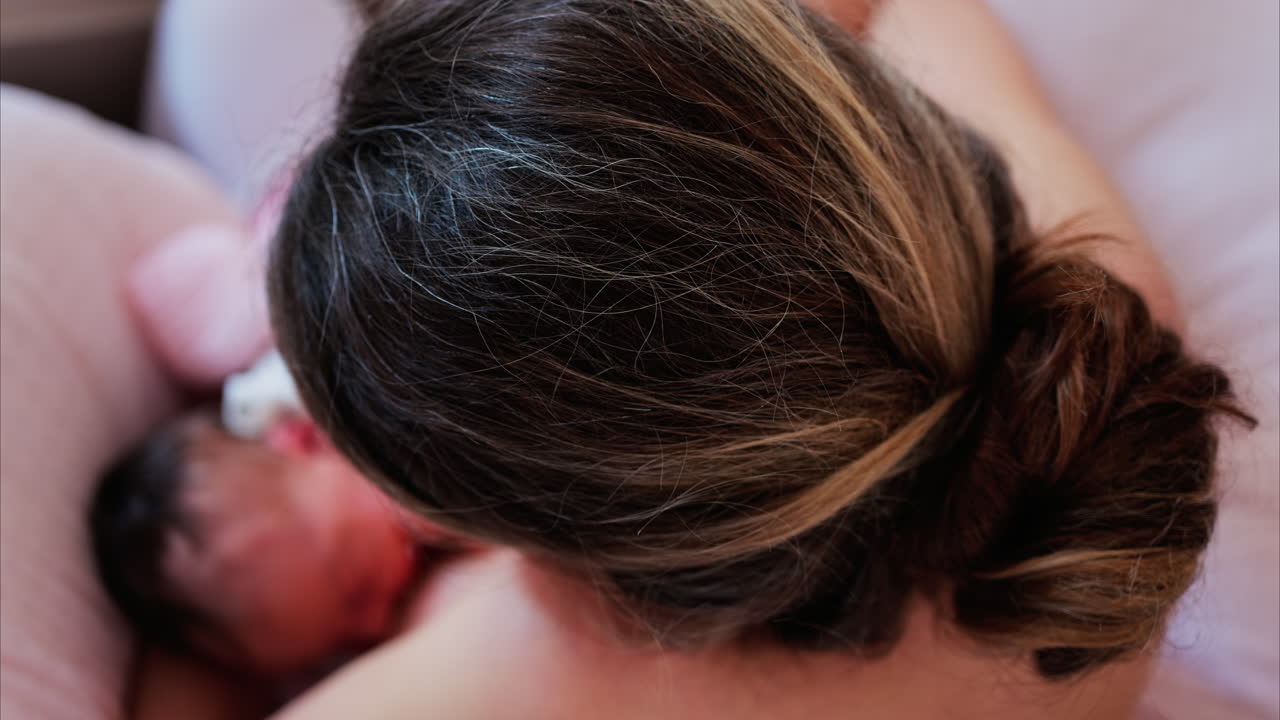 Overhead shot of a mother breastfeeding her newborn baby in a quiet, nurturing environment