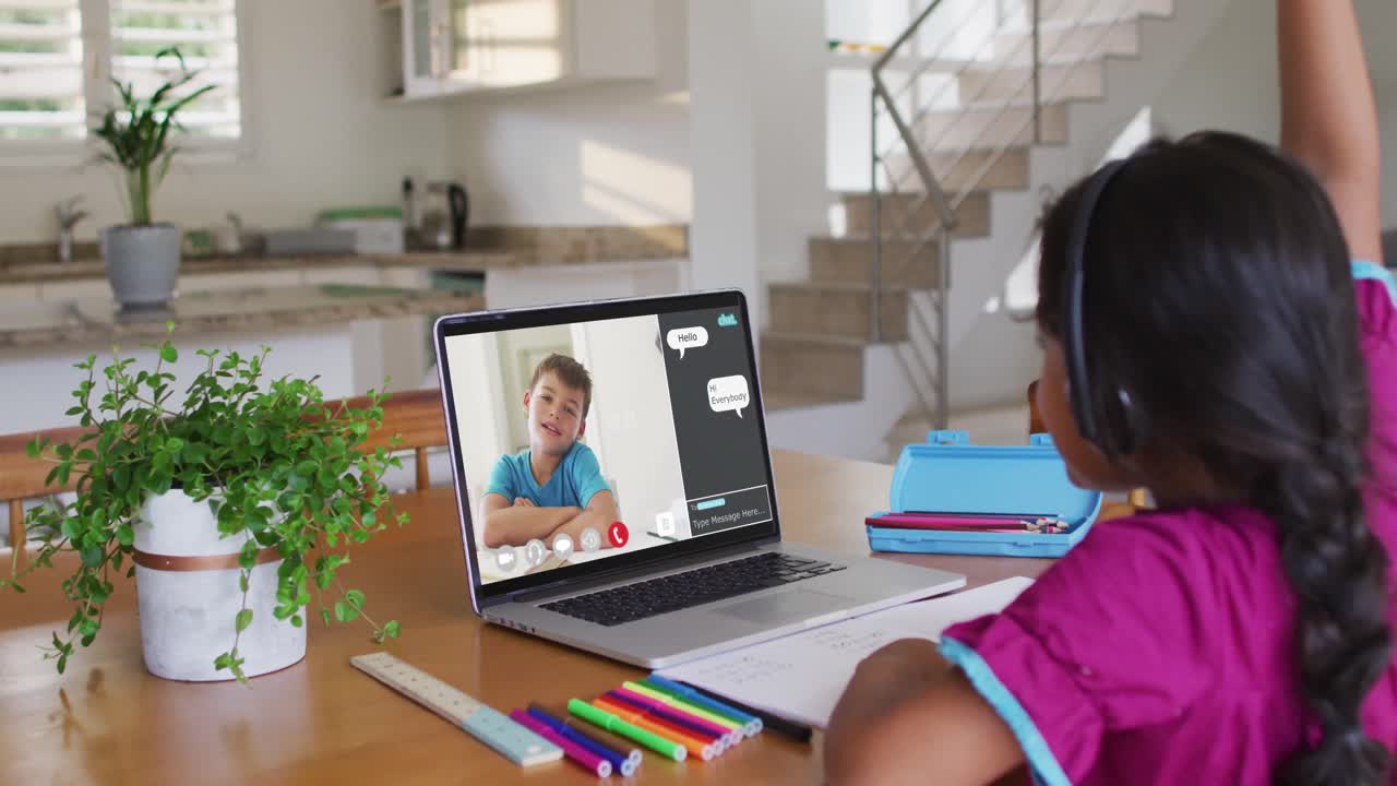 Schoolgirl using laptop for online lesson at home, with schoolboy and web chat on screen
