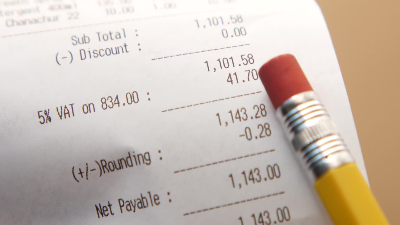 un primer plano de un recibo con un lápiz amarillo y un borrador rojo sobre él