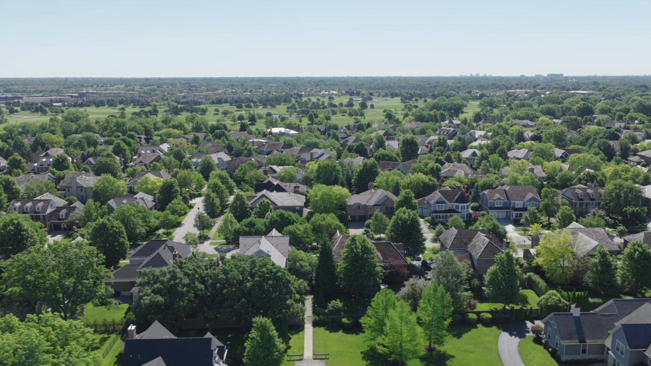 Drone flies over wealthy Glenview Illinois suburban neighborhood with large homes tree lined streets and distant golf course fairways