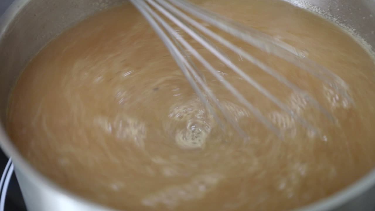 batir y cocinar mermelada de manzana en una olla de acero inoxidable