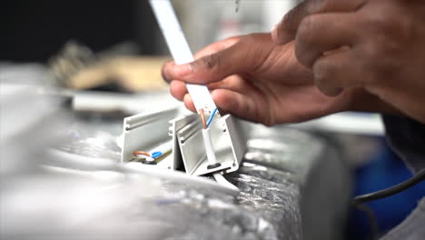 close up of a black person soldering wires with visible smoke