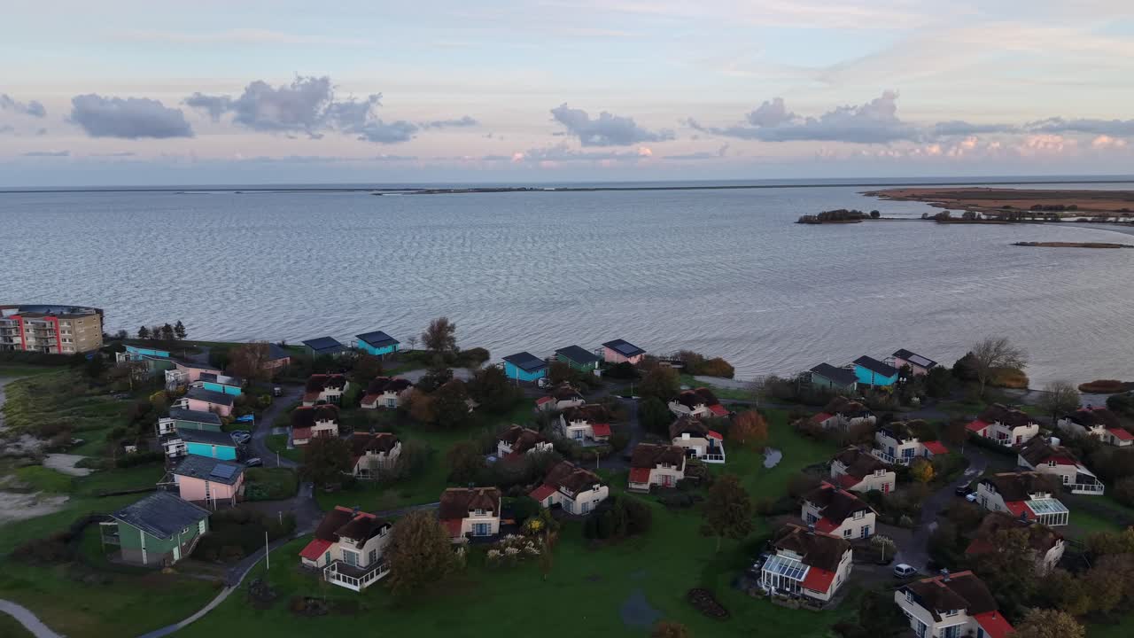 Housing area with apartment homes in Netherlands. Sunrise morning at Ijsselmeer Sea bay and coastline. Aerial lateral wide shot