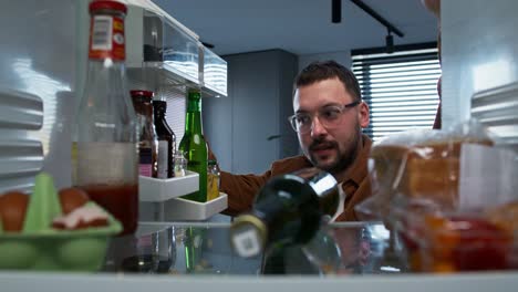 hombre buscando alimentos en el refrigerador