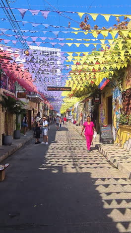 vertical view, walking on colorful authentic street in cartagena old town, colombia, old buildings and people