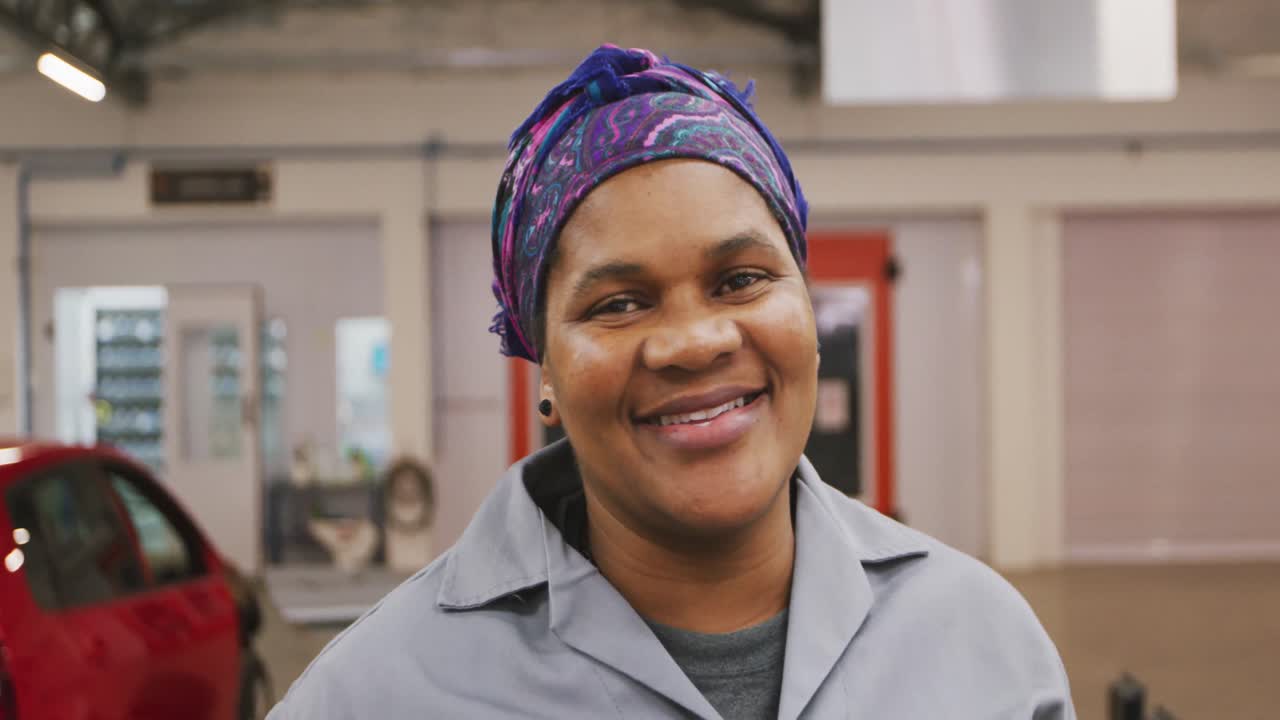 아프리카계 미국인 여성 자동차 메카닉 이 카메라 를 쳐다보고 미소 짓고 있다