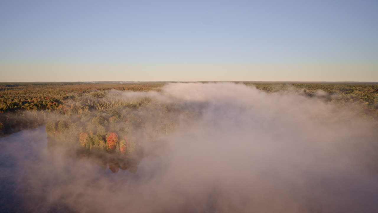 Un drone sorvola l'acqua mentre la nebbia sale nella luce del primo mattino