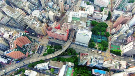 Traffic-passing-through-a-Car-park-building-in-downtown-Hong-Kong,-with-city-mega-buildings,-Aerial-view