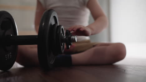 Bored-little-boy-spins-gear-with-hand-on-big-heavy-barbell