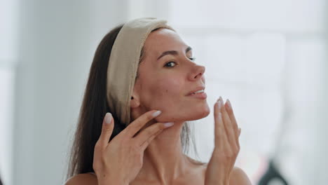 Happy-lady-applying-cream-looking-mirror-at-home-closeup.-Woman-touching-skin