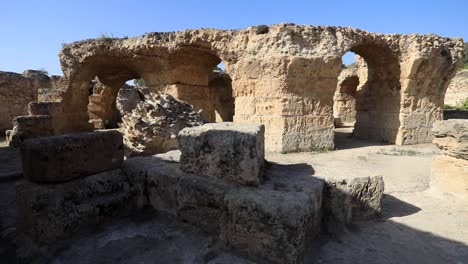 Ancient-Roman-ruins-under-clear-blue-sky-in-Carthage,-Tunisia,-with-arches-and-stones